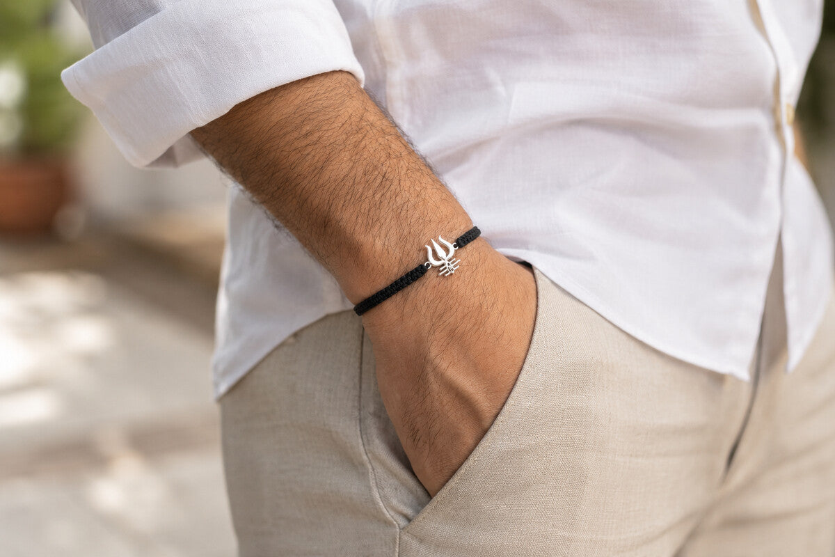 Men's Shivastra 92.5 silver bracelet with Trishul design on black cord, worn on wrist with white formal shirt